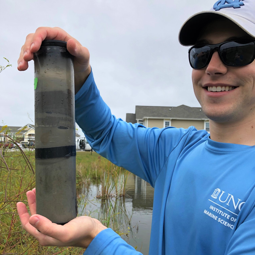 Me holding a sediment core just extracted from a pond. The coring process created some air bubbles in this core that we had to carefully release
